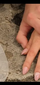 Delicate hand resting on gray stone surface with veil.