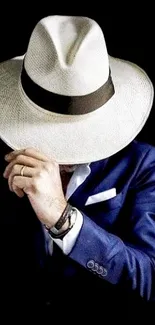 Man in blue suit and white hat on black background.