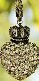 Elegant heart pendant with crown over a blurred natural background.