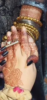 Intricate henna design with gold bangles on a hand.