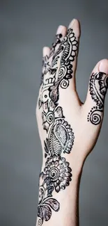 Intricate henna design on hand with light gray background.