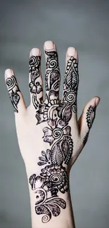 Intricate henna design on hand with gray background.