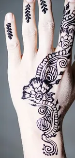 Intricate black henna design on hand against light background.