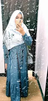 Stylish woman in blue dress with hijab taking selfie.