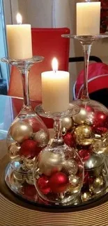 Festive candles on wine glasses with ornaments on a table.