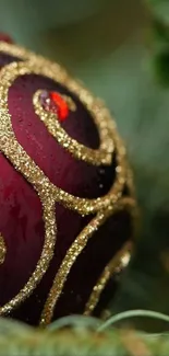 Burgundy ornament with gold swirls on pine leaves.