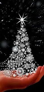 Elegant mobile wallpaper of a silver Christmas tree in a hand on black background.