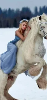 Woman in blue dress on white horse in winter landscape.