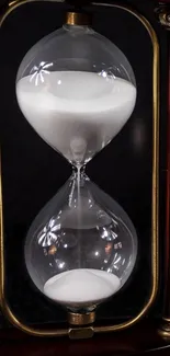 Elegant hourglass in mahogany frame with glass sand timer.