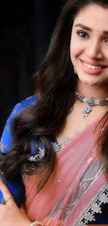 Woman in Indian attire with jewelry, smiling.