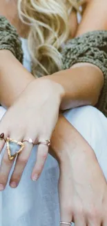 Close-up of hands with elegant jewelry against a beige background.