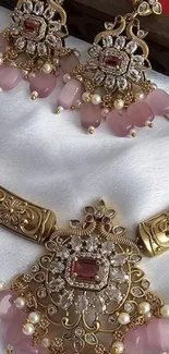 Elegant gold and pink jewelry displayed on white fabric.