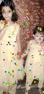 Two children in matching beige outfits against a floral background.