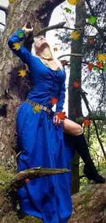 Woman in vibrant blue dress standing against a tree in a forest setting.