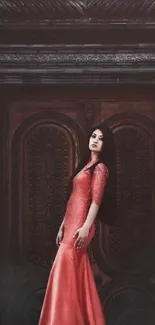 Woman in a red gown poses elegantly against a decorative wooden door.