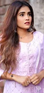 Woman in lavender dress with a brick wall background.