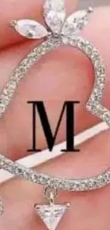 Heart-shaped pendant with letter M and diamonds.