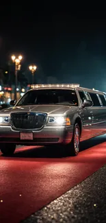 Luxurious limousine parked on a red carpet at night.