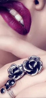 Close-up of purple lips with floral ring jewelry.