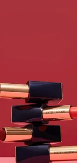 Stacked luxury lipsticks against red background.