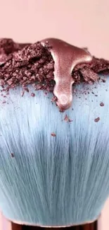 Elegant makeup brush with pastel blue bristles and shimmering pigment.