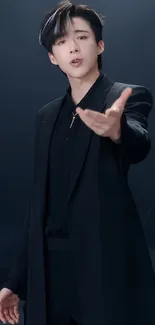 Stylish young man in a sleek black suit on a dark background.