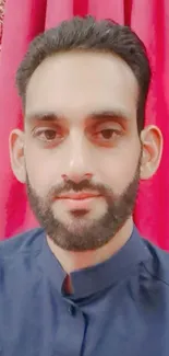 Man posing with red drapery backdrop.