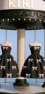 Black dresses with pink bows on mannequins in a carousel display.