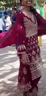 Woman in maroon traditional dress, spinning elegantly.