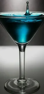 Elegant martini glass with blue liquid splash on gradient background.