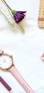 Minimalist desk setup with watch, notebook, and flower.