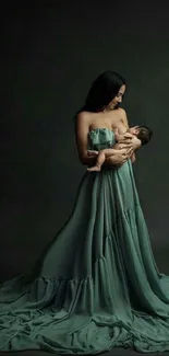 A mother in a flowing green dress holds a baby against a dark backdrop.