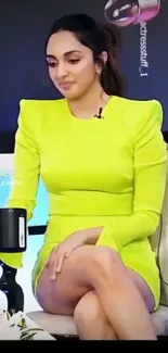 Person in neon green dress seated holding a mug.