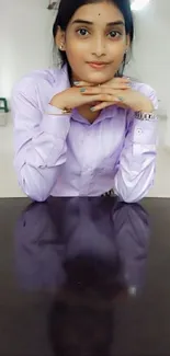 Elegant woman in purple blouse sits at office desk.