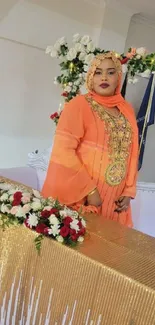 Woman in orange attire with floral decorations.