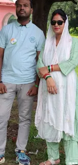 Elegant couple posing outdoor in light green and white attire.