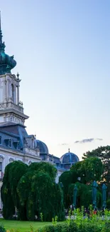 Elegant European palace with lush garden, set against a blue sky.