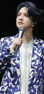 Artistic performer in vibrant jacket holding a microphone.