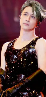 Elegant performer in sequined outfit on stage under colorful lights.