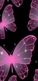 Pink glowing butterflies on a dark background wallpaper.