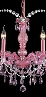 Elegant pink chandelier with crystals on black background.