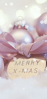 Soft pink Christmas ornaments on snow with 'Merry X-Mas' tag.