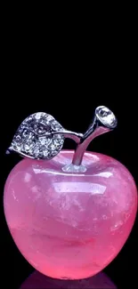 Pink crystal apple with gem leaf on black background.