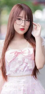 Young woman in pink dress with glasses in outdoor setting.