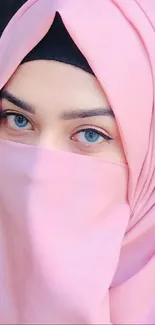 Portrait of a woman in a pink hijab with striking blue eyes.