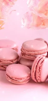 Pink macarons with floral accents on a wallpaper.