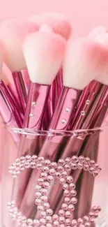 Elegant pink makeup brushes in a decorative holder.