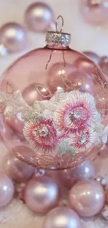 Elegant pink holiday ornament with floral embroidery on a pink background.