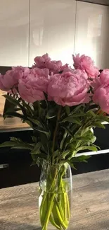 Vase of pink peonies on a wooden table.