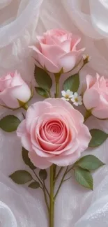 Elegant pink roses with green leaves on soft fabric background.